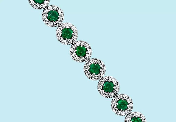 Zoomed in for detail of a May birthstone bracelet of brilliant cut emeralds framed in diamond halos set in white gold