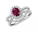 An oval-cut ruby split-shank engagement ring accented by a round-cut diamond halo converging with two white gold bands adorned with rows of pavé-set diamonds