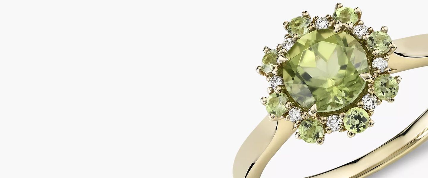 An August birthstone ring of peridot round-cut center gemstone surrounded by diamond and more peridot stones as floral petals and set in yellow gold