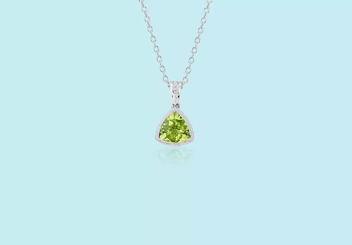 A trillion-cut August birthstone pendant of bezel-set peridot surrounded by vintage-inspired milgrain accent in white gold hanging from white gold cable chain
