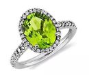 A peridot and diamond halo engagement ring of vibrant green oval peridot birthstone gemstone center framed by a halo of pavé set round brilliant-cut diamonds