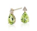 A pair of teardrop-shaped peridot earrings topped each with a trio of diamonds set in yellow gold