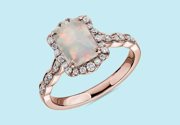 An October birthstone ring with emerald-cut opal surrounded by floral diamond halo and rose gold setting