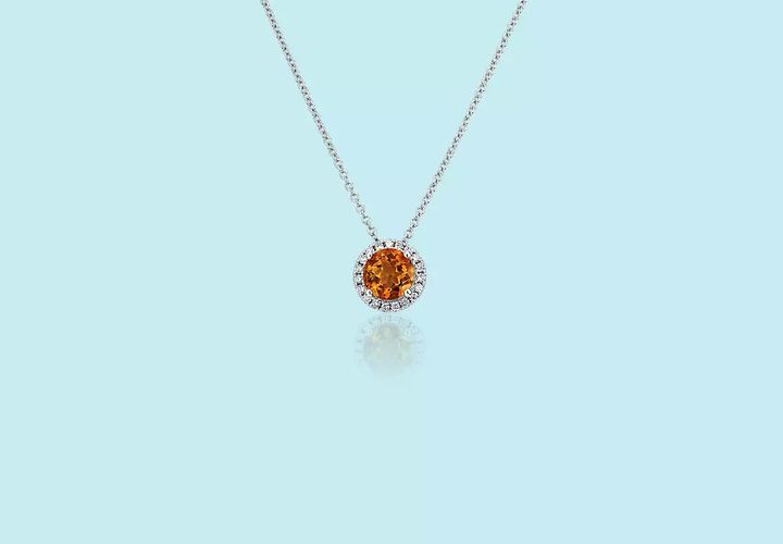 A November birthstone halo necklace of a round-cut citrine gemstone centered in diamond pavé with matching cable chain in white gold