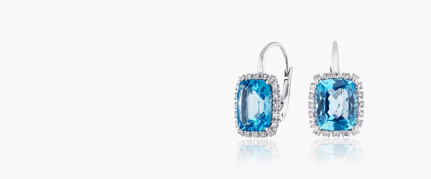 A pair of cushion-cut December birthstone earrings of Swiss Blue Topaz detailed with diamond halos set in white gold lever back drops