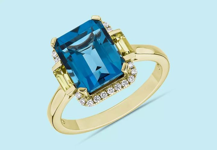 A December birthstone ring of emerald-cut London blue topaz framed with two emerald cut peridot gemstones set in yellow gold