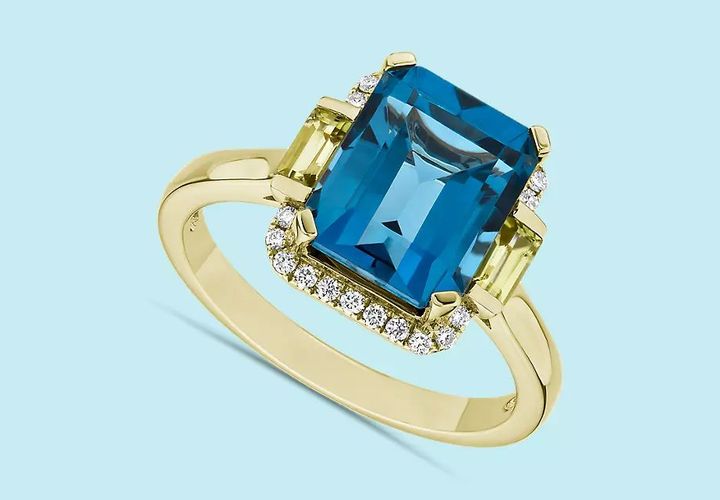 A London blue topaz engagement ring with octagon cut center framed with two emerald cut peridot gemstones in yellow gold