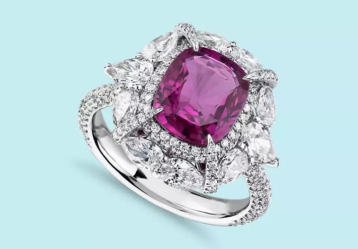 A radiant cut pink sapphire engagement ring set in diamond halo pave and circled in pear shaped diamond accents set in white gold