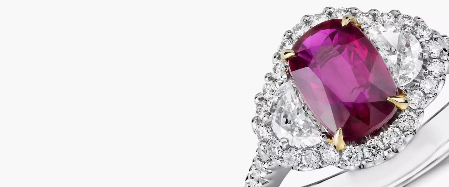 A cushion cut ruby engagement ring accented by half moon diamond and halo setting