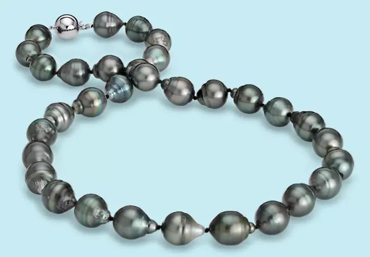 An 18 inch strand of iridescent black Tahitian pearls in  10 millimeter off-round baroque shapes held by a white gold box clasp