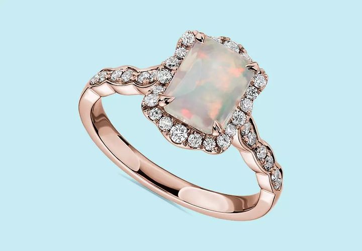An emerald cut opal engagement ring accented with with floral diamond halo and rose gold setting