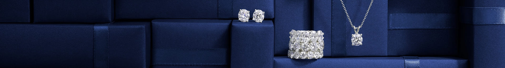 Elegant display of sparkling diamond jewelry including rings, earrings, a necklace, and a bracelet against a backdrop of luxurious blue gift boxes