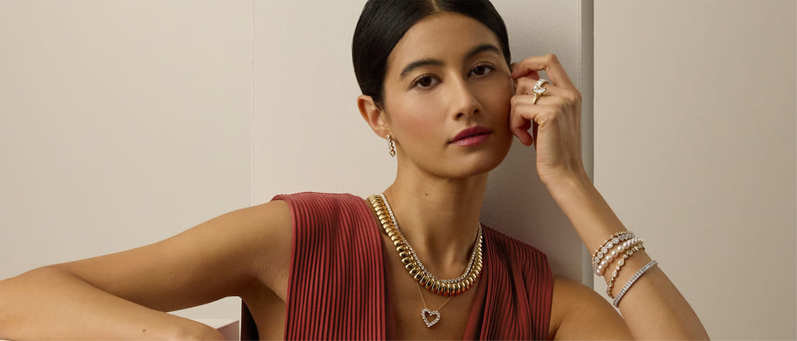 Woman in a red dress wearing gold jewelry, including a necklace, rings, and bracelets.