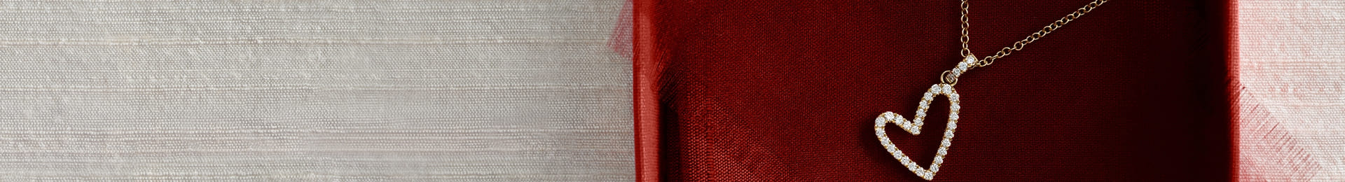 Gold heart-shaped pendant necklace on a red textured background.