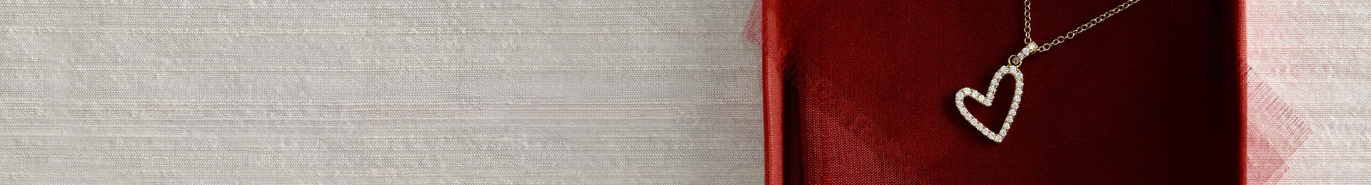 Gold heart-shaped pendant necklace on a red textured background.