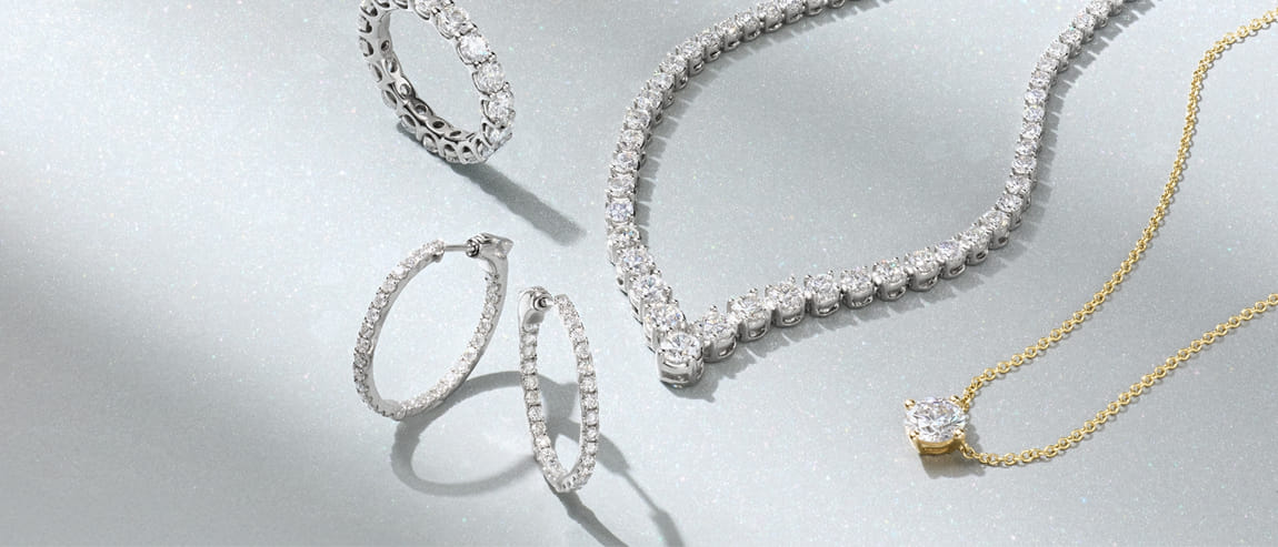 Collection of diamond jewelry including rings, earrings, and necklaces on a sparkling surface.
