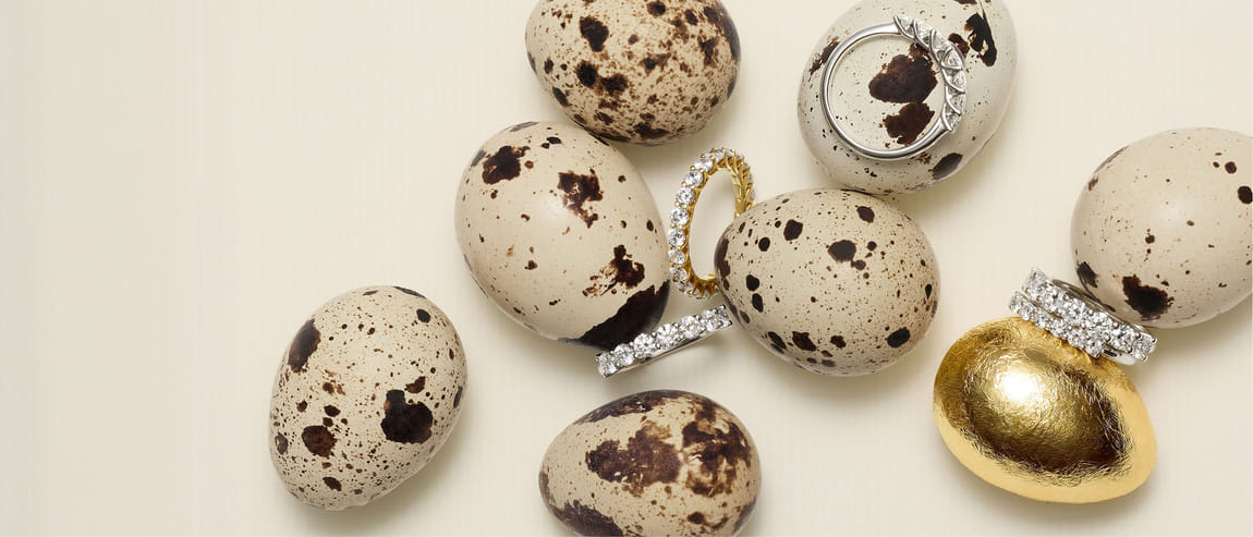 Speckled and gold eggs paired with diamond rings on a light background.
