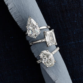 Three diamond rings with different cuts displayed on a blue fabric.