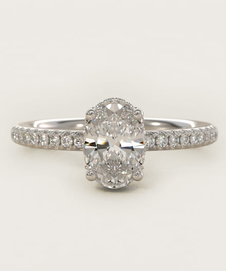 Elegant oval diamond ring with a diamond-studded band on a light background.