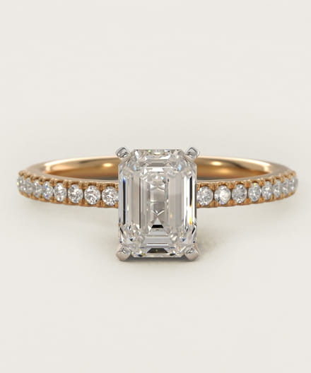 Emerald cut diamond ring with a gold band featuring side gemstones.