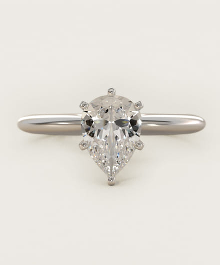 Pear-shaped diamond ring with a sleek silver band on a light background.