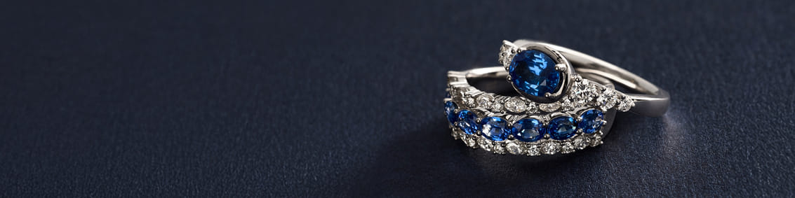 Silver ring set with blue and clear gemstones on a dark surface.