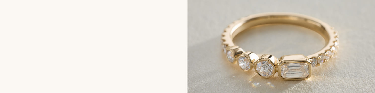 Gold band ring with round and rectangular diamonds on a light surface.