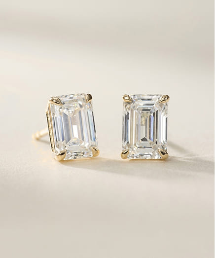 Elegant gold and diamond rectangular stud earrings on a light background.