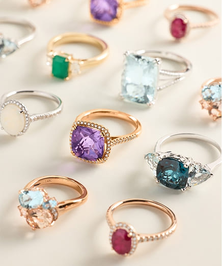 Assorted gemstone rings displayed on a light surface.