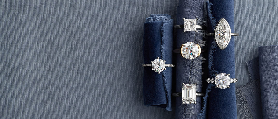 Assorted diamond rings displayed on rolled blue fabric