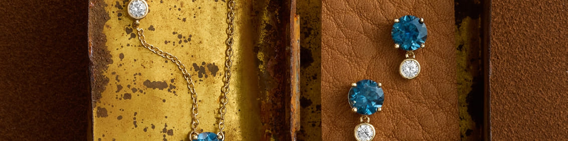 Jewelry with blue gemstones and diamonds on a rustic brown surface.