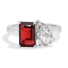 A ring with a rectangular red gem and a teardrop-shaped diamond on a silver band.