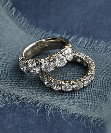 Two diamond rings on a blue textured fabric background.