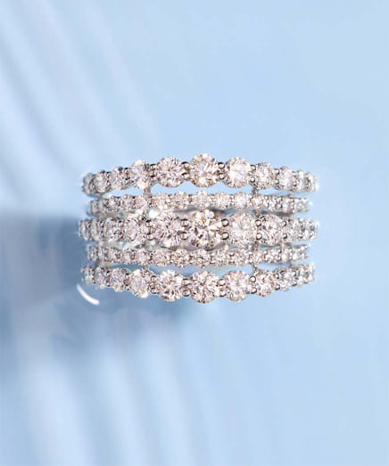 Stack of sparkling diamond rings set against a blue background.