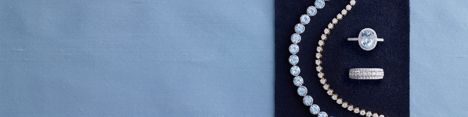 Elegant arrangement of diamond jewelry on a dark blue background.