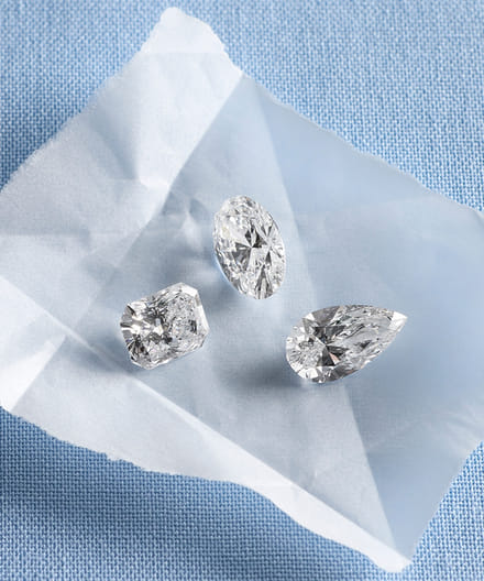 Three diamonds in different cuts on a light blue textured background.