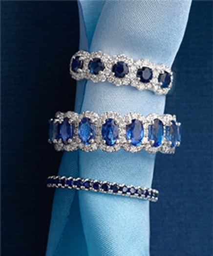 Three sapphire and diamond rings displayed on a blue ribbon.