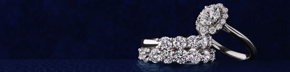 Diamond engagement and wedding rings with a blue background.