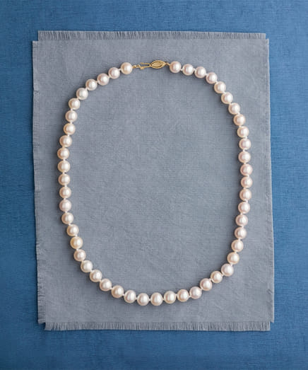 String of white pearls on a layered blue and gray fabric background.