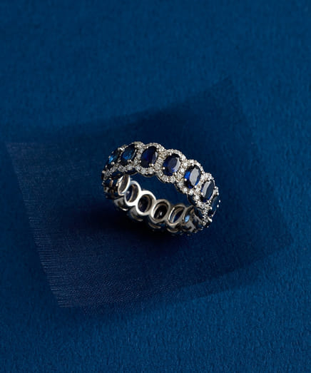 Elegant silver ring adorned with blue gemstones on a blue background.