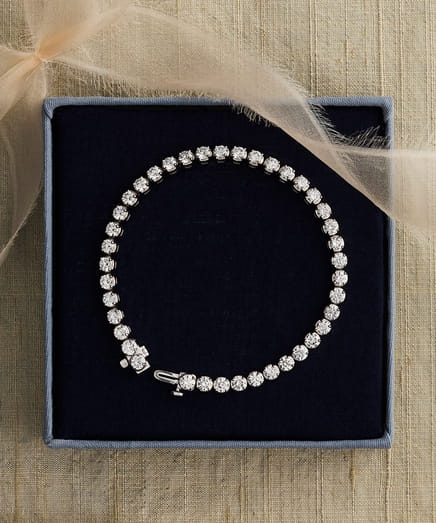 Elegant diamond bracelet in a gift box with a satin ribbon accent.
