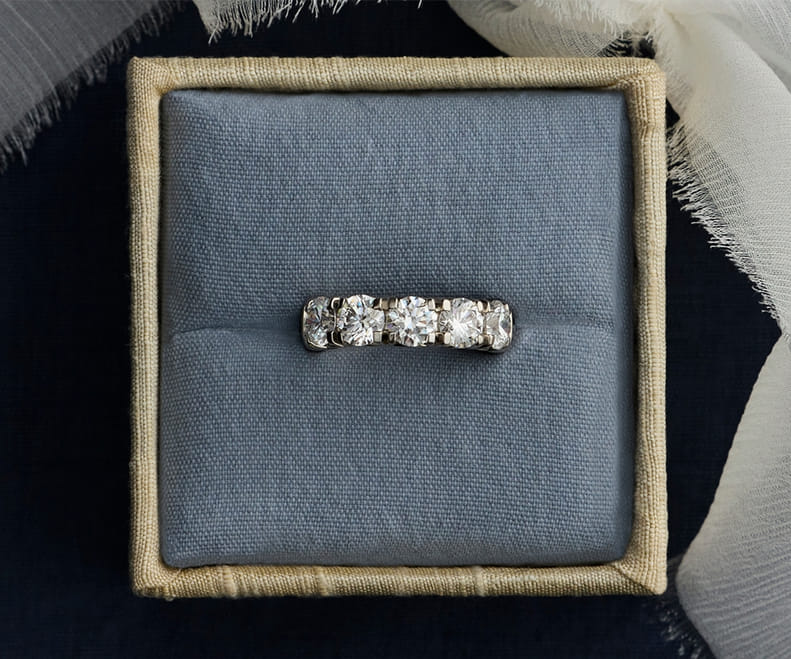 Diamond ring in a textured box with a soft fabric ribbon on a dark background. Diamond ring in a textured box with a soft fabric ribbon on a dark background.