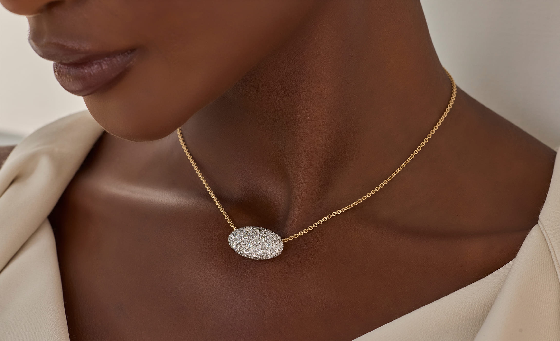 Woman wearing a gold necklace with an oval diamond pendant. Woman wearing a gold necklace with an oval diamond pendant.