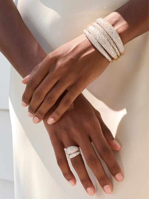Hands with sparkling stacked bracelets and ring in elegant setting. Hands with sparkling stacked bracelets and ring in elegant setting.