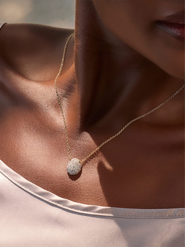 Close-up of a woman wearing a delicate gold necklace with a sparkling pendant. Close-up of a woman wearing a delicate gold necklace with a sparkling pendant.