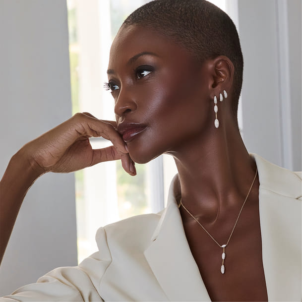 Profile of a woman wearing elegant pearl earrings and necklace in a bright room. Profile of a woman wearing elegant pearl earrings and necklace in a bright room.