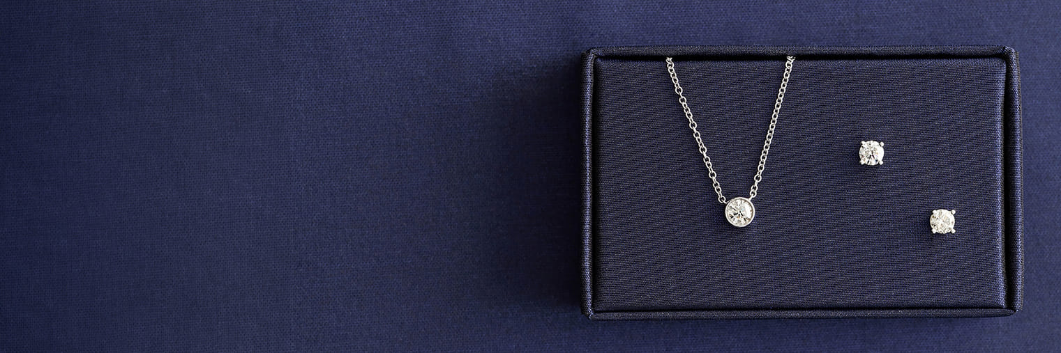 Silver necklace and earrings set displayed in a navy box