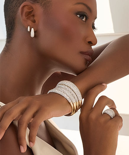 Woman showcasing diamond jewelry including earrings, bracelets, and a ring.