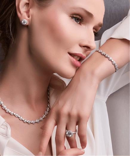 Woman wearing diamond earrings, necklace, bracelet, and ring.