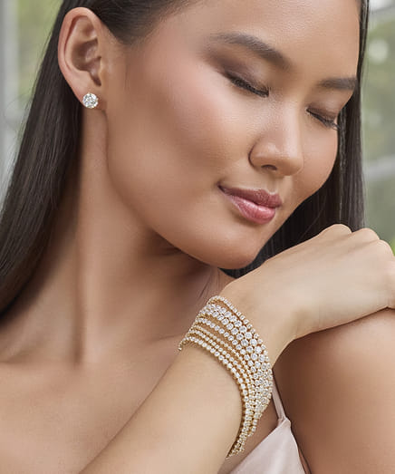 Woman wearing diamond earrings and bracelet with a serene expression.